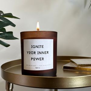 NIKITA Empowering amber frosted glass candle, labelled 'Ignite your inner power'. Featuring a powerful and warming sea salt and sage scent. Christmas or birthday home decor gift for her.