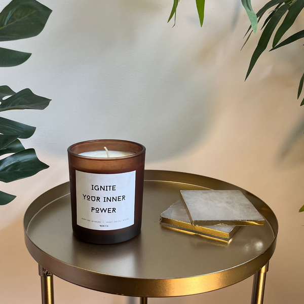 NIKITA Empowering amber frosted glass candle, labelled 'Ignite your inner power'. Featuring a powerful and warming sea salt and sage scent. Christmas or birthday home decor gift for her.