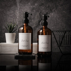NIKITA amber glass dispenser bottle set with stainless steel pumps for your kitchen or bathroom. Durable soap dispensers with waterproof labels for hand soap, dish soap, hand lotion or hand sanitiser.